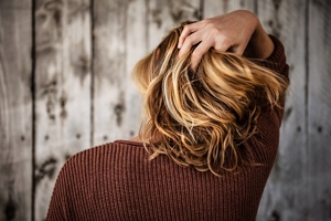 Woman with blonde balayage running her hand through her hair